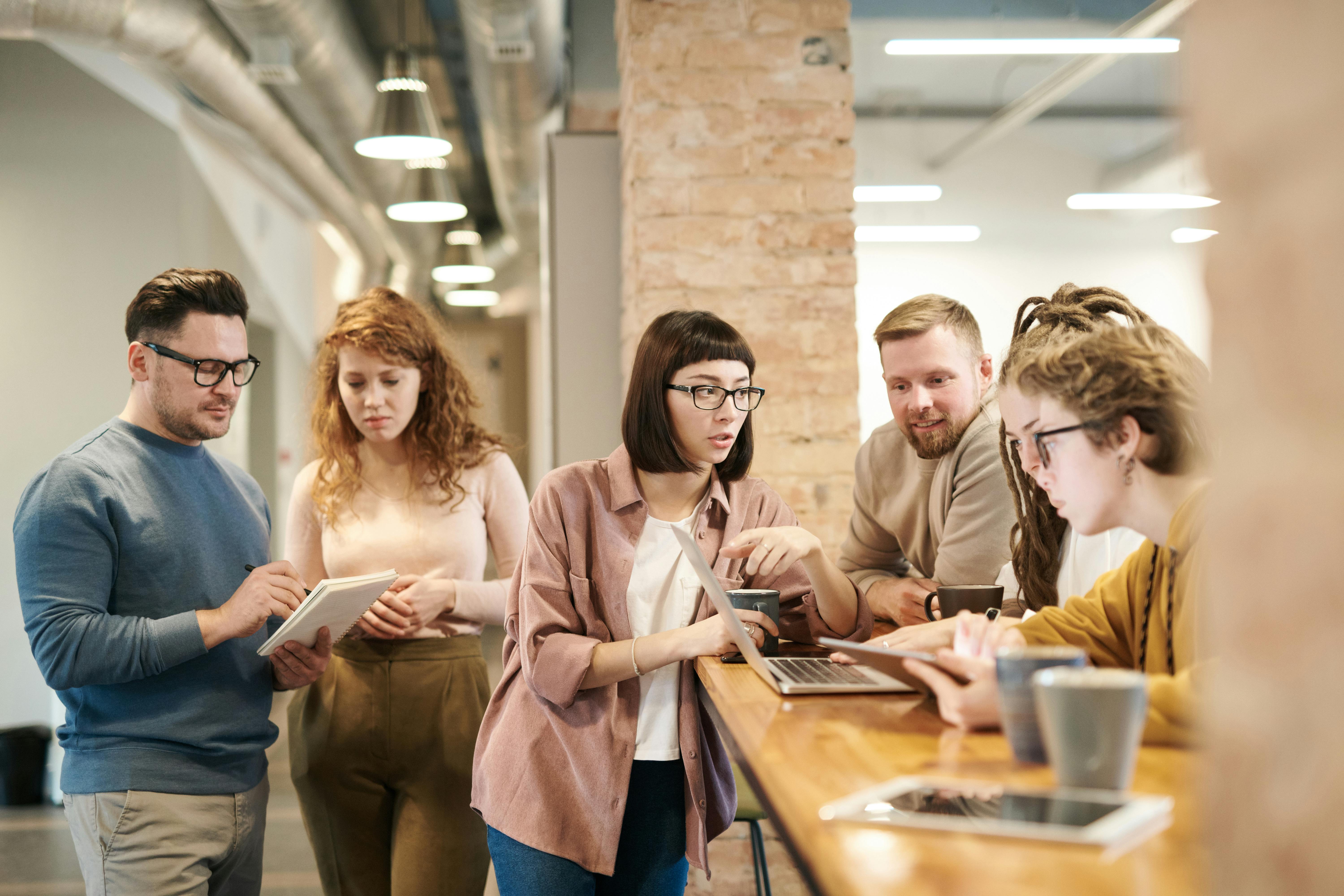 A team gathered around a table with laptops and tablets in an open office.
