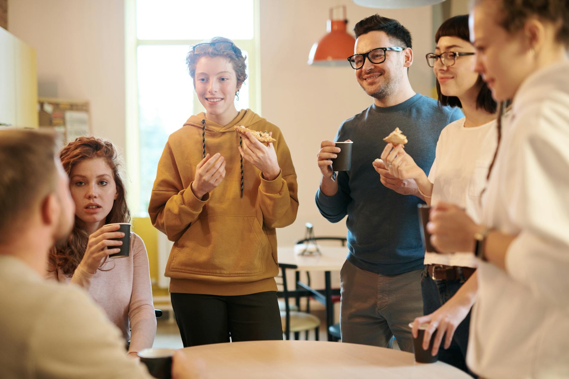 Team members standing in an office kitchen, sharing snacks.